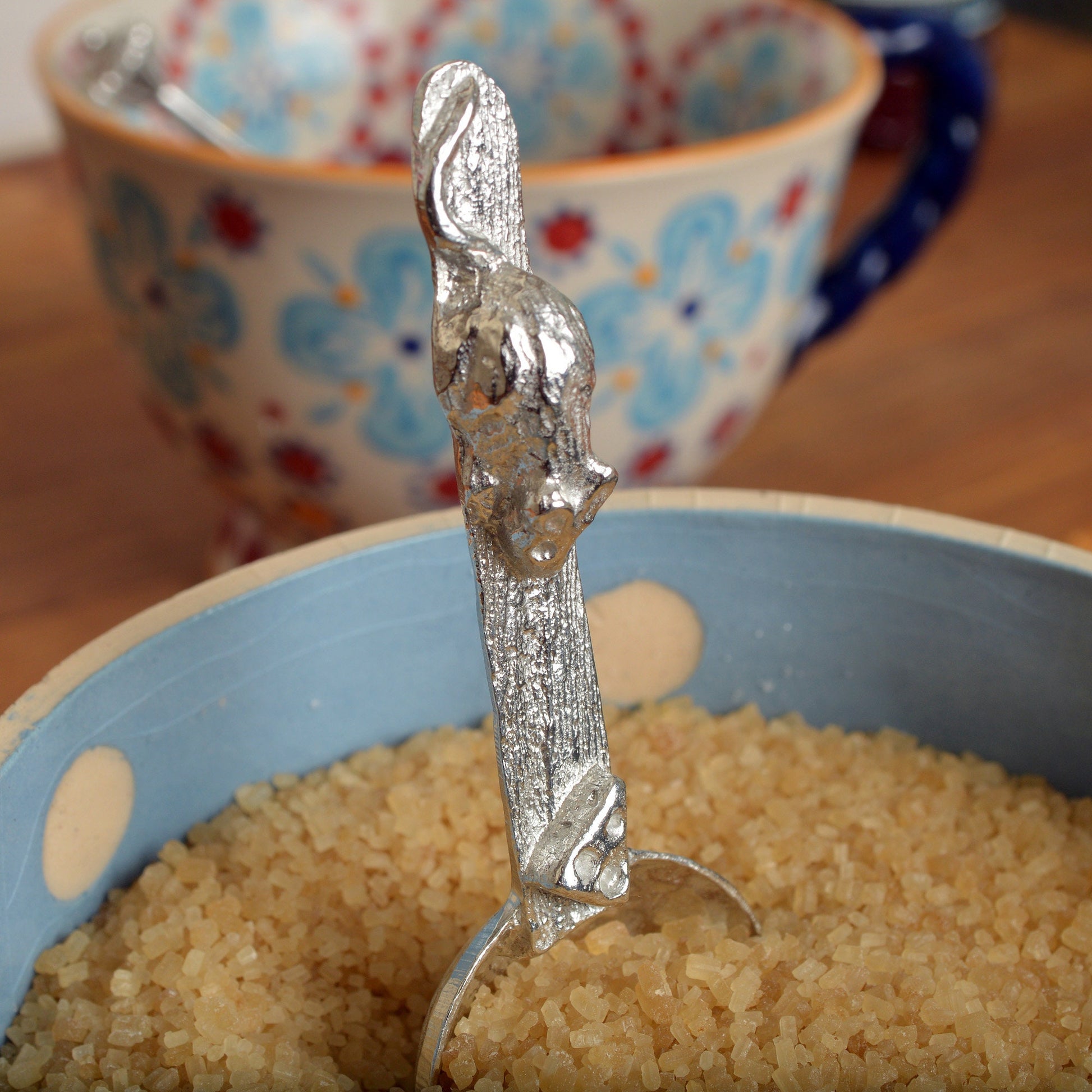 A small spoon pewter sugar spoon. A round bowled spoon leads to a wood textured stem with a mouse chasing a wedge of cheese. Practical & useful mouse gifts for nature lovers. UK handmade