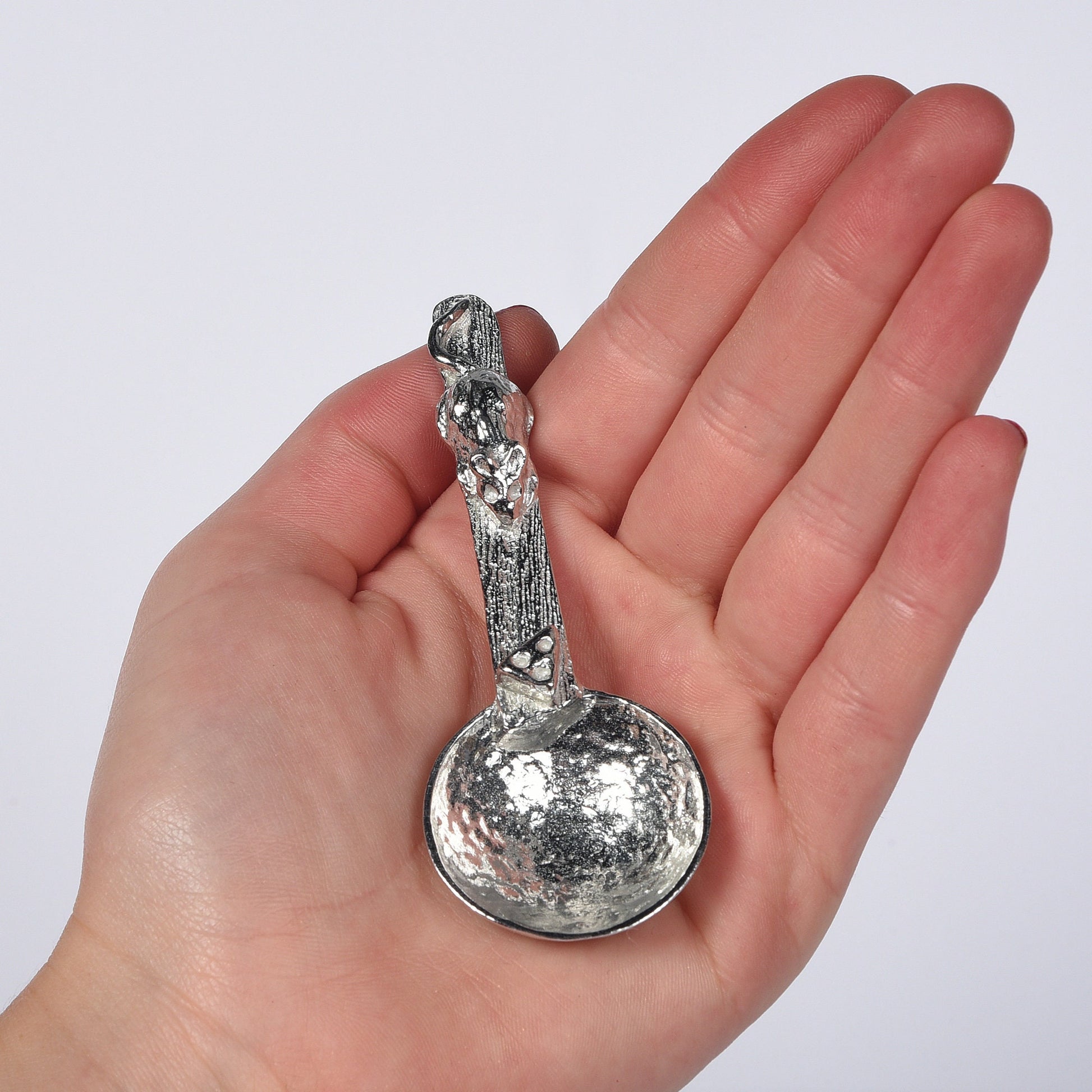 A small spoon pewter sugar spoon. A round bowled spoon leads to a wood textured stem with a mouse chasing a wedge of cheese. Practical & useful mouse gifts for nature lovers. UK handmade