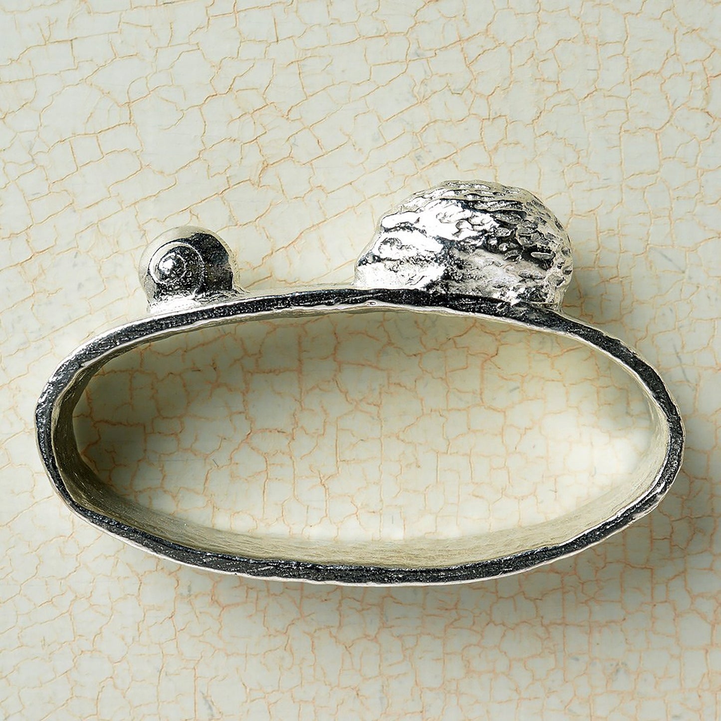 A set of 6 textured pewter oval-shaped napkin rings. Each one has a sculpture of an animal persuing its favourite food. A hedgehog and snail, a mouse and cheese, a frog and insect, a rabbit and carrot, a tortoise and leaf and a squirrel and acorn.