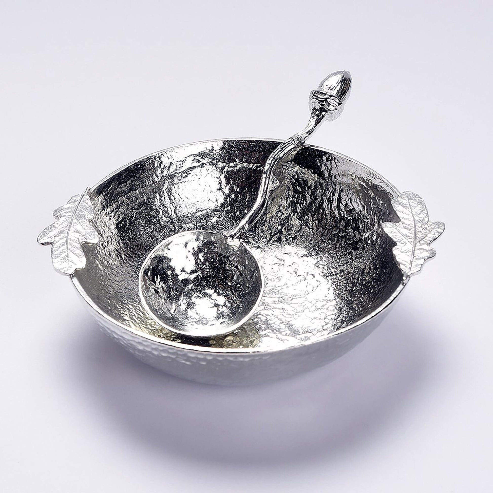 A 9cm diameter textured circular pewter bowl, with two oak leaves on the edge of the dish, comes with accompanying acorn spoon. Gifts for nature lovers, oak and acorn gifts. 'Great oaks from little acorns grow'.