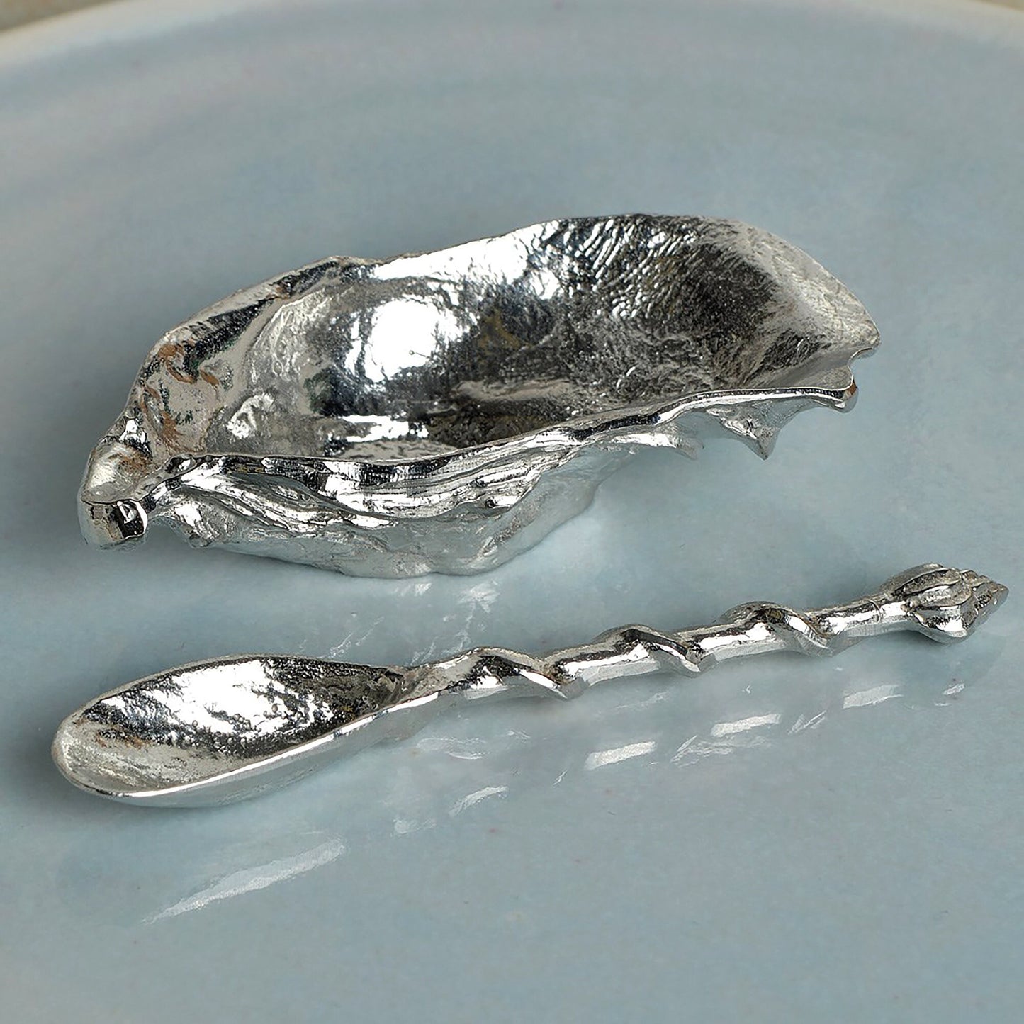 A beautifully detailed pewter oyster shell shaped bowl and mussel spoon set. The silver coloured oyster bowl is ideal for sea salt, sugar, mustard etc. The accompanying spoon has a mussel shell bowl and a small shell finial on an entwining stem.